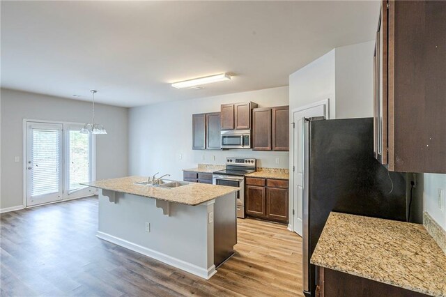 1003 Eldon Ln, Fairburn, GA 30213 - kitchen with stainless steel appliances, an island with sink, dark brown cabinetry, light wood-style flooring, and a kitchen bar