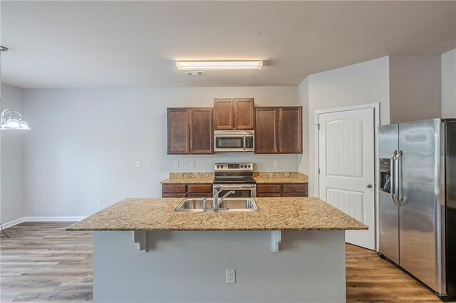 1003 Eldon Ln, Fairburn, GA 30213 - kitchen featuring light wood-type flooring, stainless steel appliances, a kitchen breakfast bar, and a sink
