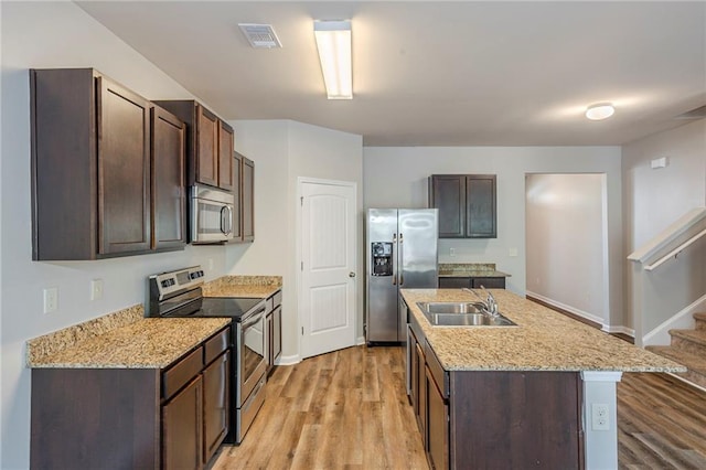 1003 Eldon Ln, Fairburn, GA 30213 - kitchen with light wood finished floors, appliances with stainless steel finishes, dark brown cabinets, and a sink