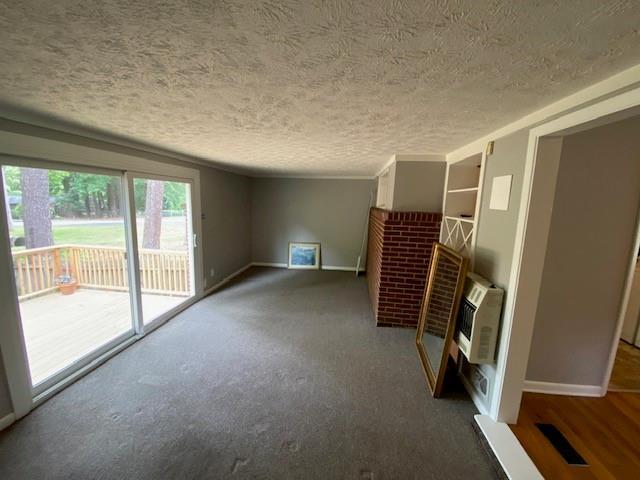 1177 Baker Ln, Marietta, GA 30062 - unfurnished living room with a textured ceiling, heating unit, baseboards, carpet, and a fireplace