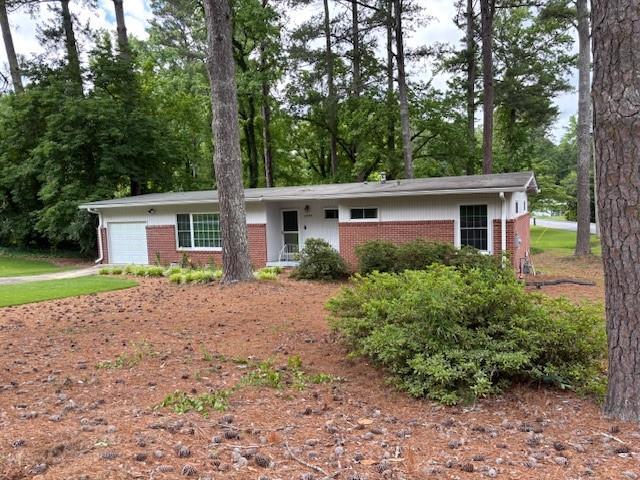 1177 Baker Ln, Marietta, GA 30062 - single story home featuring brick siding, a garage, view of wooded area, and driveway