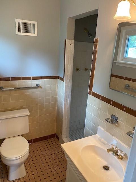 1177 Baker Ln, Marietta, GA 30062 - full bathroom with tile walls, a shower stall, toilet, wainscoting, and tile patterned floors