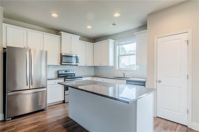 235 Orchard Dr, Covington, GA 30014 - kitchen featuring stainless steel appliances, stone countertops, decorative backsplash, a center island, and white cabinets