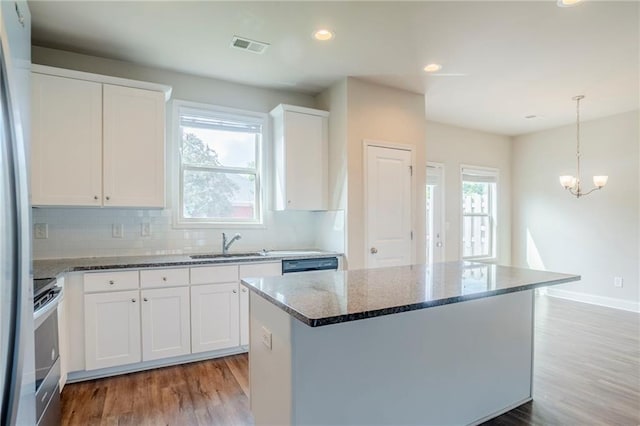 235 Orchard Dr, Covington, GA 30014 - kitchen with stainless steel appliances, dark stone counters, a chandelier, light wood-type flooring, and tasteful backsplash