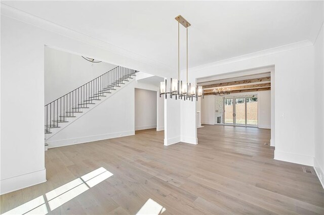 unfurnished dining area featuring a chandelier, baseboards, stairs, ornamental molding, and wood finished floors