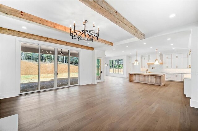 unfurnished living room featuring wood finished floors, a chandelier, recessed lighting, and beamed ceiling