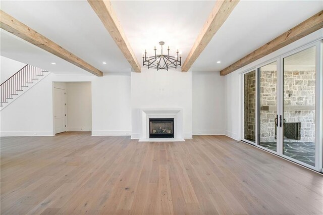 unfurnished living room featuring beamed ceiling, baseboards, stairs, a fireplace, and light wood-type flooring