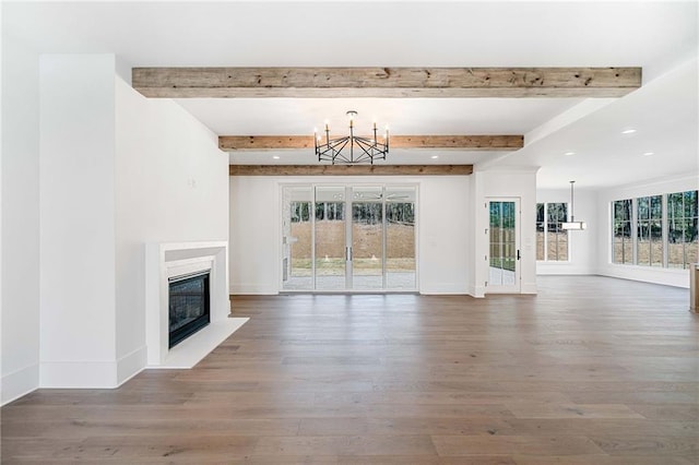 unfurnished living room with wood finished floors, a glass covered fireplace, and plenty of natural light