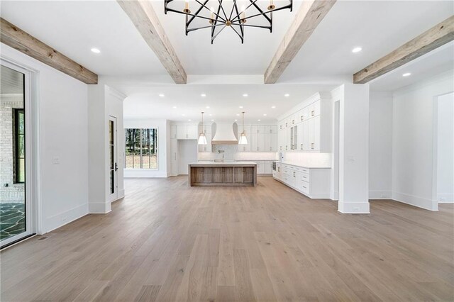 kitchen featuring backsplash, white cabinetry, light wood-type flooring, baseboards, and custom range hood