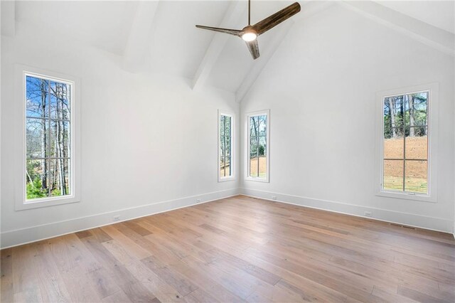 unfurnished room featuring light wood-type flooring, high vaulted ceiling, beam ceiling, and a healthy amount of sunlight