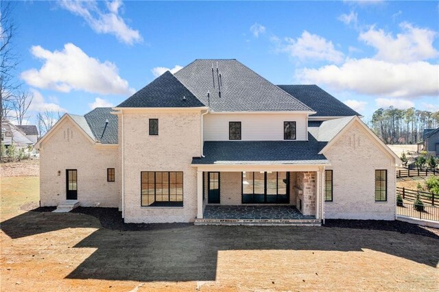 back of house featuring brick siding, a shingled roof, fence, and a patio area