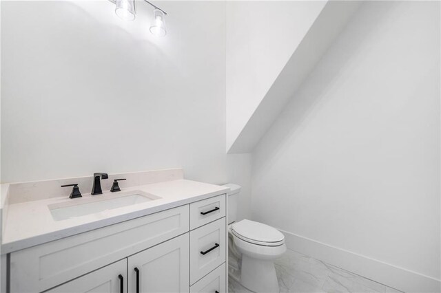 bathroom with marble finish floor, baseboards, toilet, and vanity