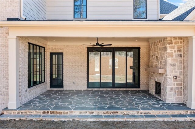 entrance to property with brick siding, a ceiling fan, and a patio area
