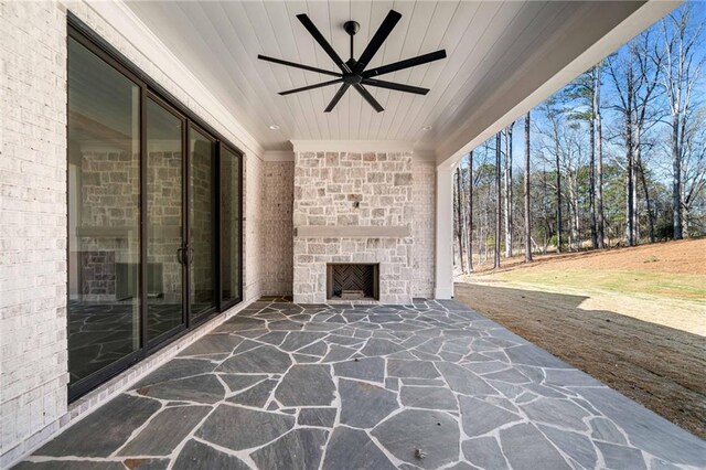 view of patio with a ceiling fan and an outdoor stone fireplace