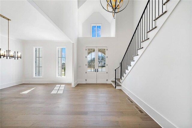 foyer entrance featuring visible vents, wood finished floors, stairway, and a notable chandelier