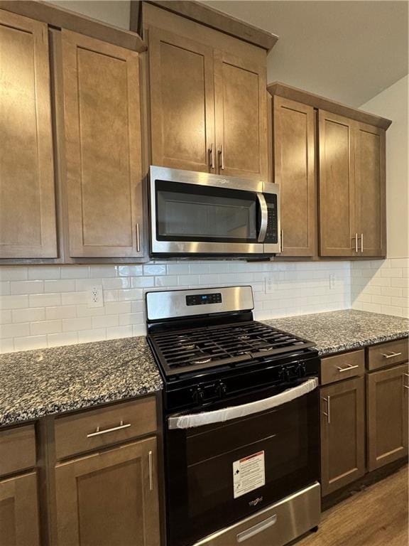 2277 Whitworth St, Lawrenceville, GA 30044 - kitchen featuring appliances with stainless steel finishes, dark stone countertops, backsplash, and wood finished floors