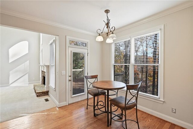 403 Pebblebrooke Ln, Canton, GA 30115 - dining room featuring ornamental molding, baseboards, light wood-style floors, a fireplace with raised hearth, and a chandelier