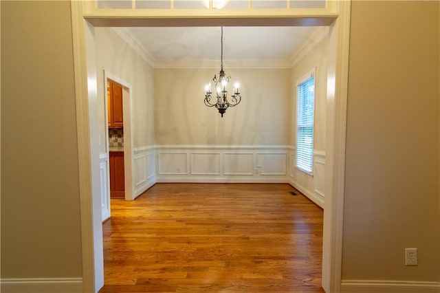 403 Pebblebrooke Ln, Canton, GA 30115 - unfurnished dining area featuring a chandelier, light wood-style floors, ornamental molding, a wainscoted wall, and a decorative wall