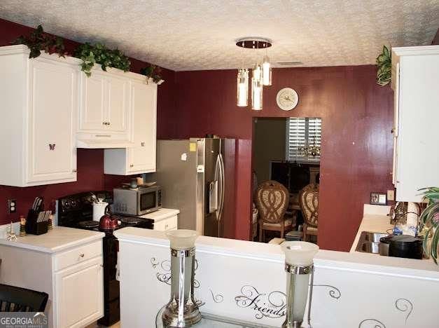 978 Francis Ln, Fairburn, GA 30213 - kitchen with stainless steel appliances, a textured ceiling, white cabinets, light countertops, and under cabinet range hood