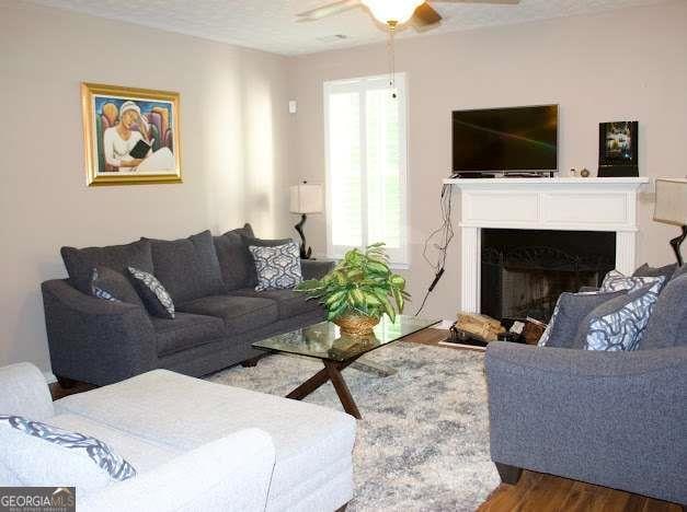 978 Francis Ln, Fairburn, GA 30213 - living room featuring wood finished floors, a ceiling fan, and a fireplace