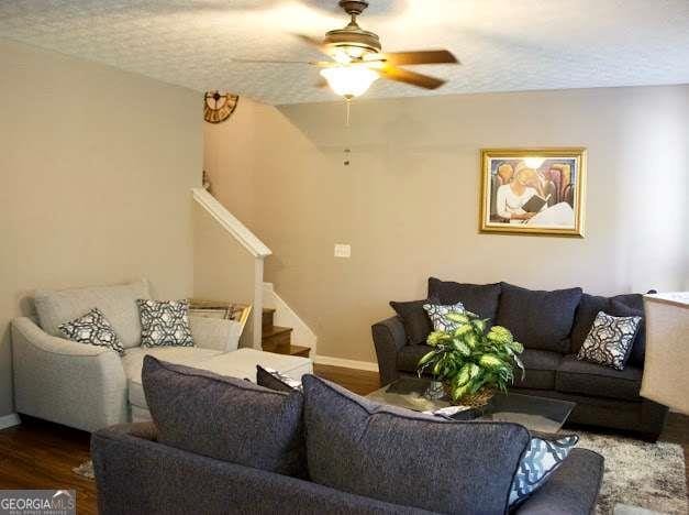 978 Francis Ln, Fairburn, GA 30213 - living room with stairway, wood finished floors, a ceiling fan, and a textured ceiling