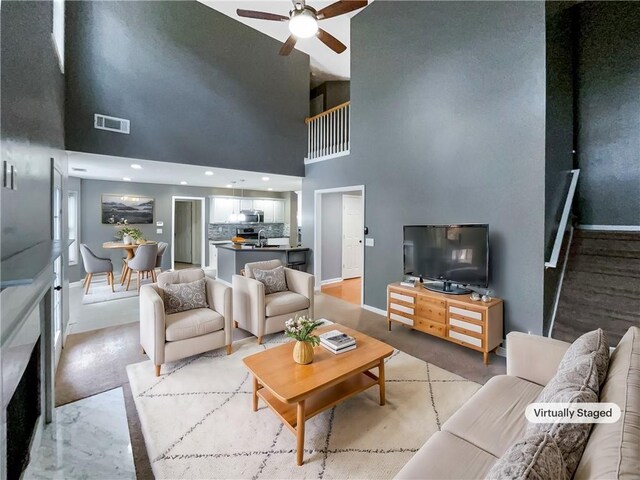 living room featuring ceiling fan, a towering ceiling, and sink