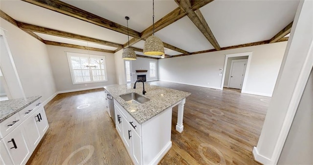 kitchen with white cabinetry, a kitchen island with sink, sink, and pendant lighting