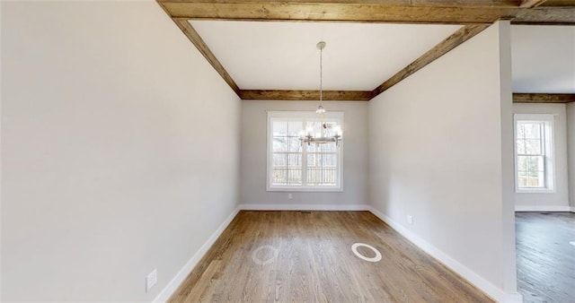 unfurnished dining area featuring beam ceiling, wood-type flooring, and an inviting chandelier