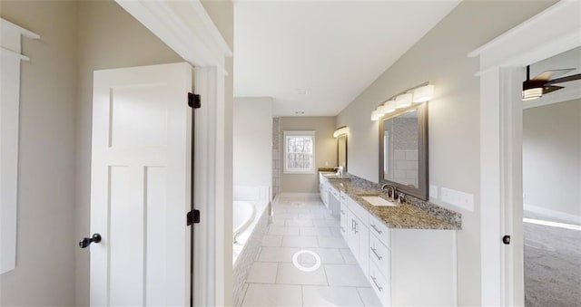 bathroom with tile patterned floors, vanity, and a relaxing tiled tub