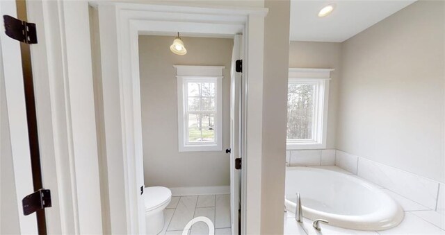 bathroom featuring a healthy amount of sunlight, a bath, and toilet