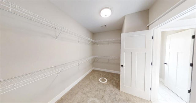 walk in closet featuring light colored carpet