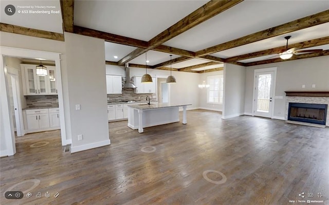 kitchen with ceiling fan, dark hardwood / wood-style floors, an island with sink, pendant lighting, and white cabinets