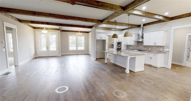 kitchen featuring a center island with sink, light hardwood / wood-style flooring, beamed ceiling, decorative light fixtures, and white cabinetry