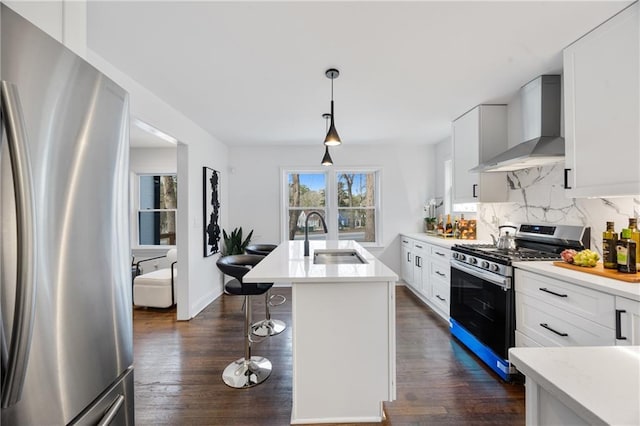 kitchen featuring appliances with stainless steel finishes, wall chimney exhaust hood, a sink, dark wood-style floors, and light countertops