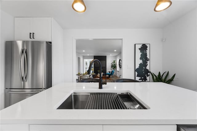 kitchen with freestanding refrigerator, a sink, light countertops, white cabinetry, and recessed lighting