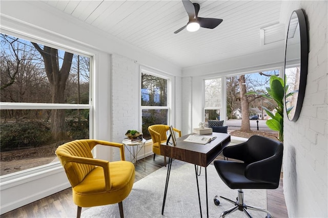 sunroom featuring wood finished floors and brick wall