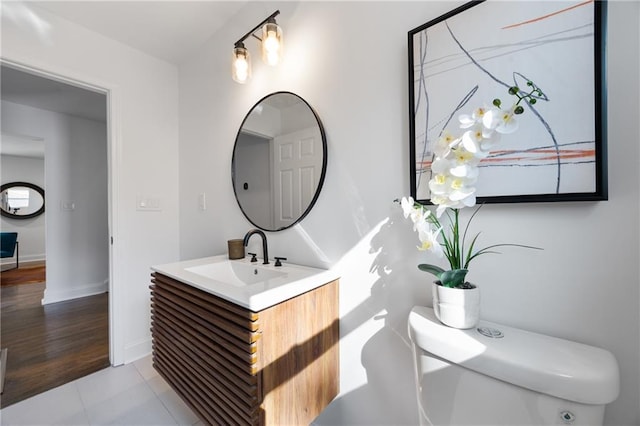 half bath with toilet, vanity, baseboards, and tile patterned flooring