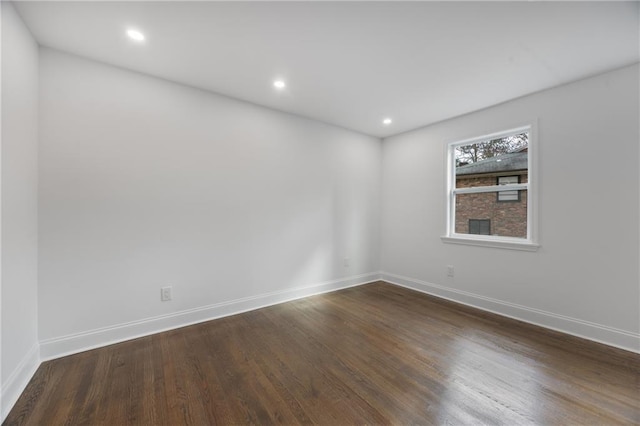 empty room with dark wood-style flooring, baseboards, and recessed lighting