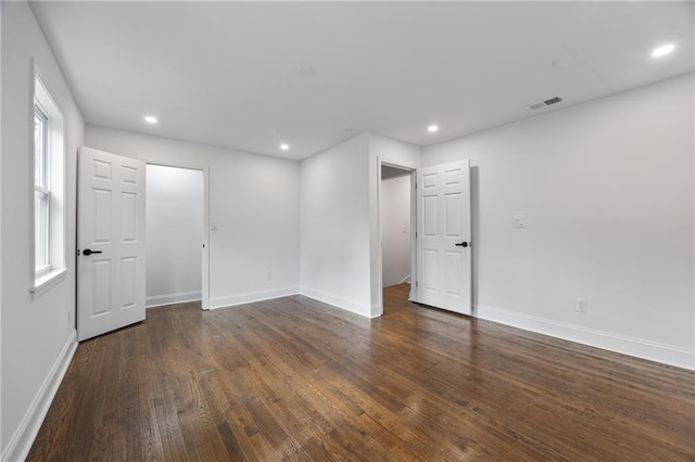 empty room with wood finished floors, baseboards, and recessed lighting