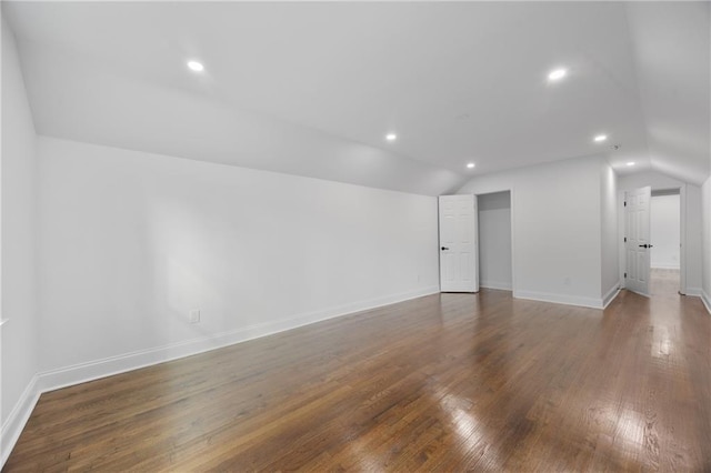 empty room featuring lofted ceiling, wood finished floors, baseboards, and recessed lighting