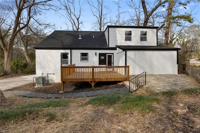 rear view of property featuring a deck, central AC unit, a patio area, and a shingled roof