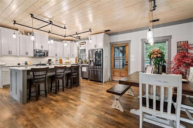 kitchen featuring a center island, dark wood-type flooring, stainless steel appliances, and hanging light fixtures