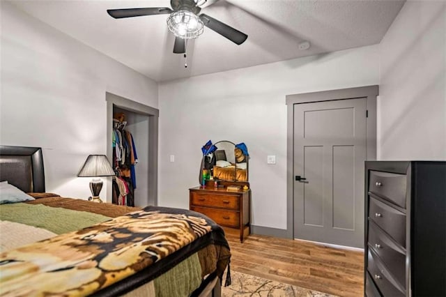 bedroom with light hardwood / wood-style floors, a closet, a textured ceiling, and ceiling fan