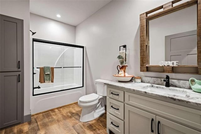 full bathroom with vanity, toilet, hardwood / wood-style flooring, and shower / bath combination with glass door