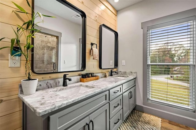 bathroom featuring a wealth of natural light, vanity, hardwood / wood-style flooring, and wood walls