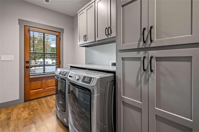 washroom with washer and dryer, light hardwood / wood-style floors, and cabinets