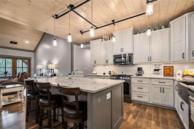 kitchen with appliances with stainless steel finishes, white cabinets, a center island, and decorative light fixtures