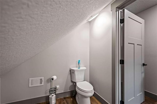 bathroom featuring a textured ceiling, hardwood / wood-style flooring, and toilet