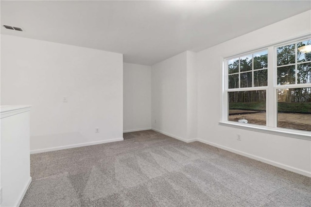 carpeted empty room with a healthy amount of sunlight, visible vents, and baseboards