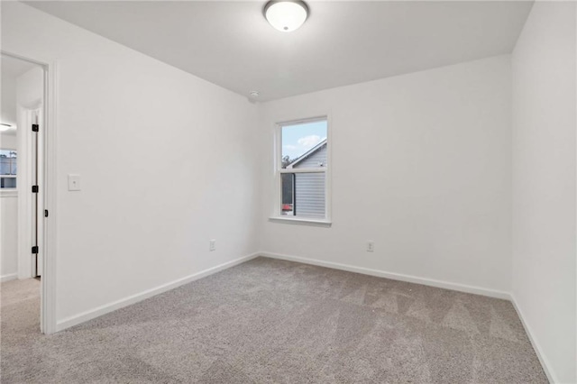 carpeted empty room featuring baseboards